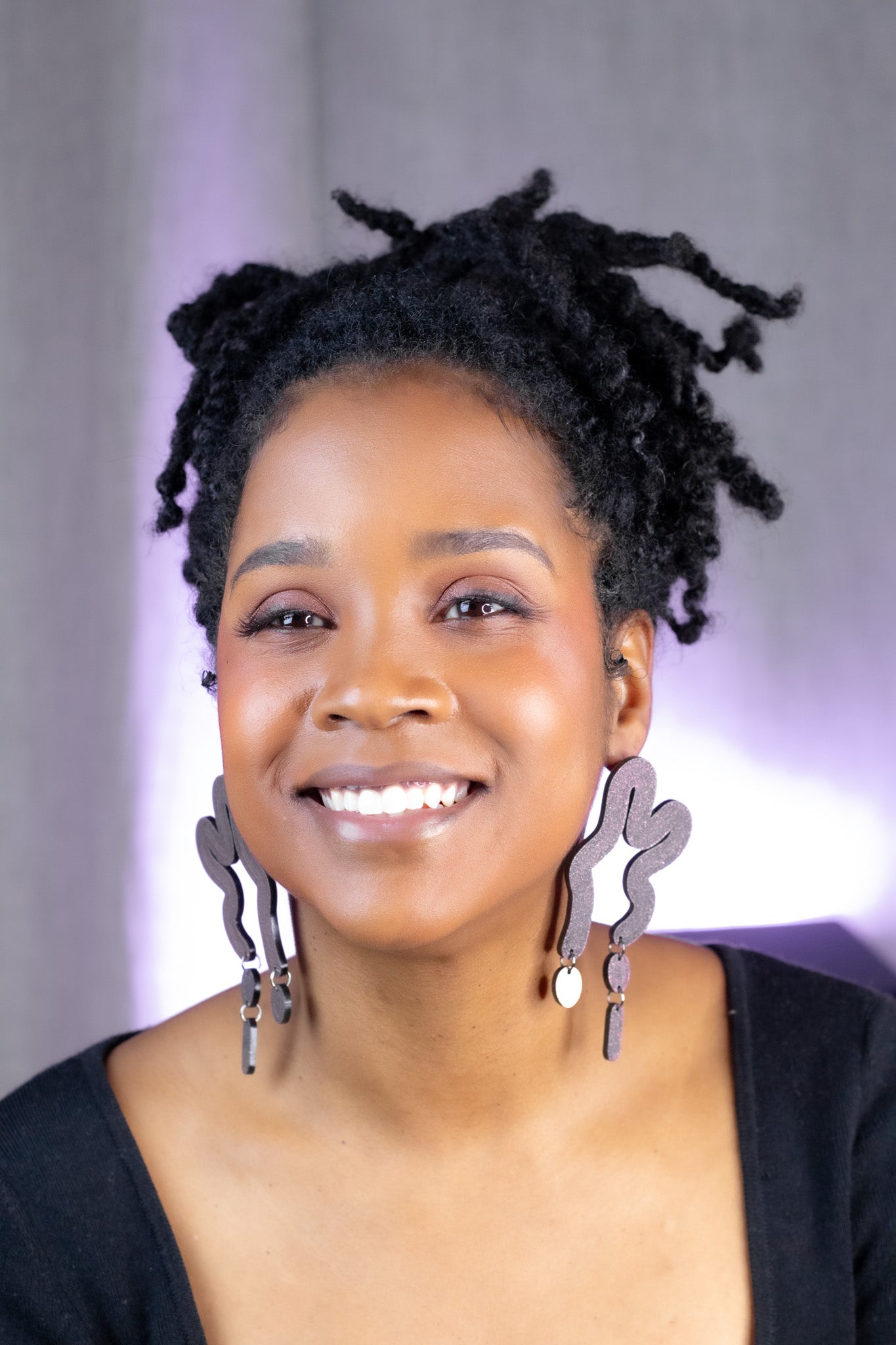 Woman with styled hair and large earrings against a neutral background
